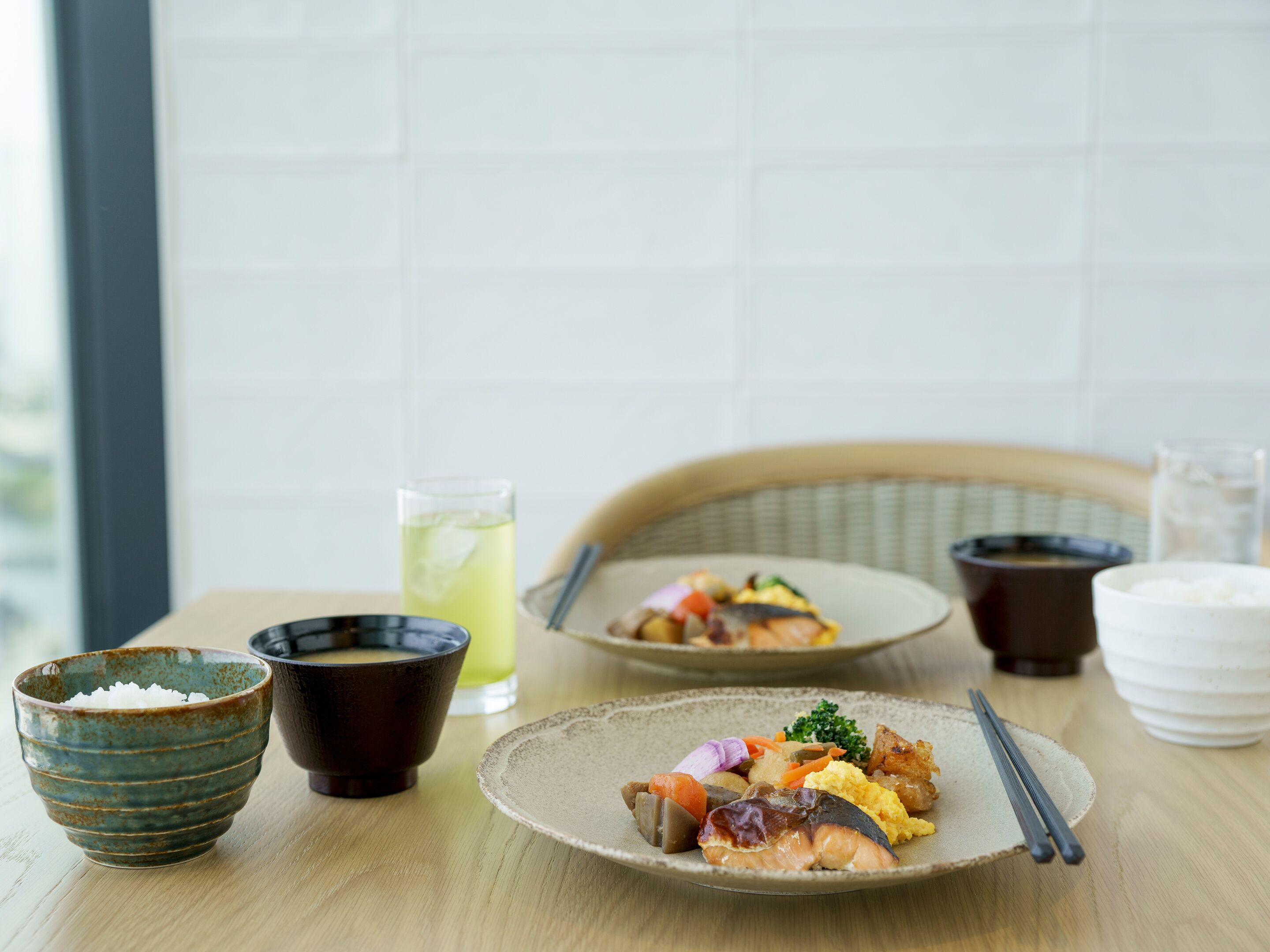 A dining table with a plate of food, a bowl of rice, a cup of tea, and a glass of water.