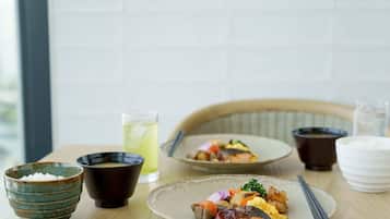 A dining table with a plate of food, a bowl of rice, a cup of tea, and a glass of water.