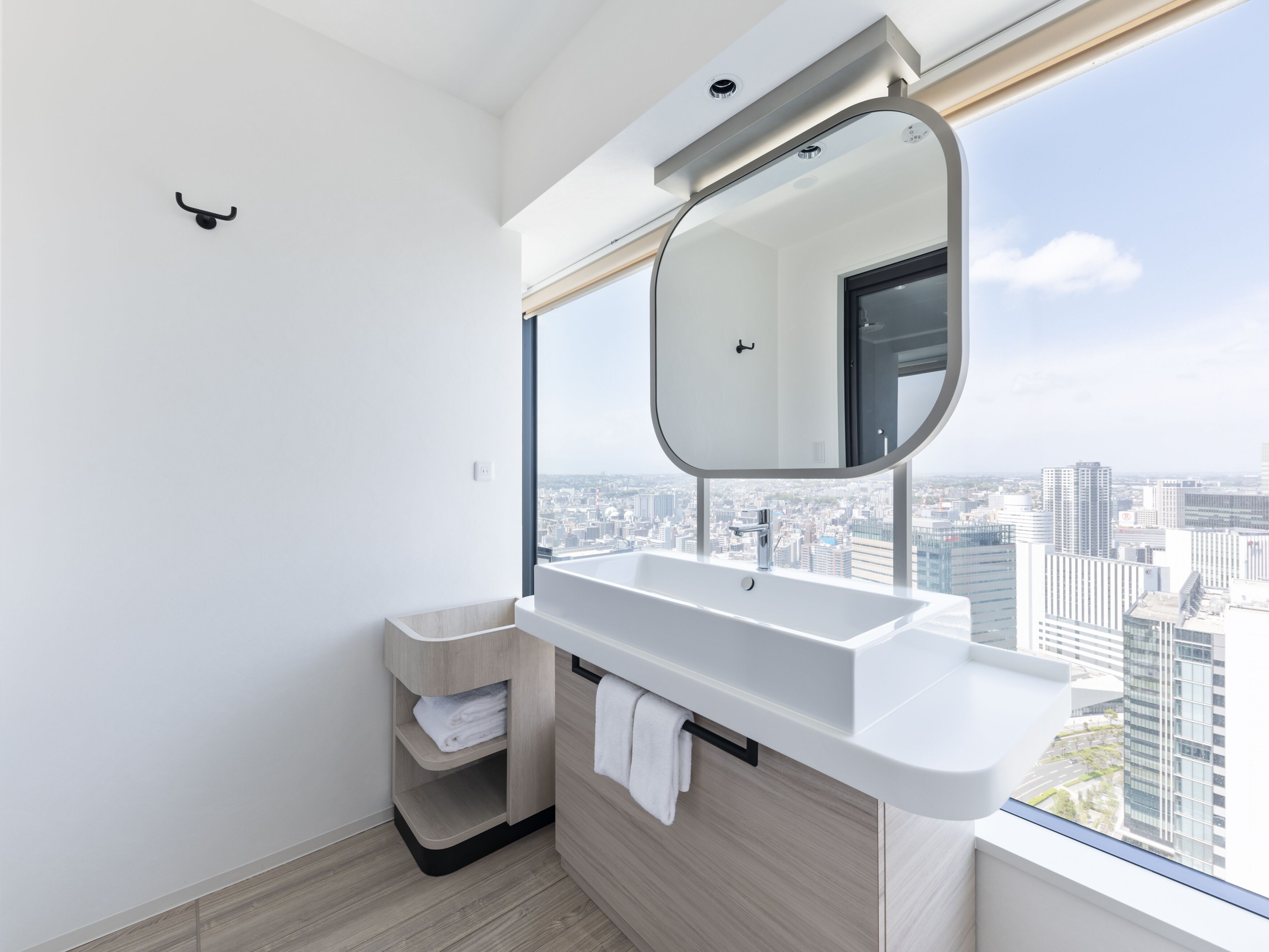 Un baño moderno con un ventanal grande, un lavamanos blanco y un espejo.