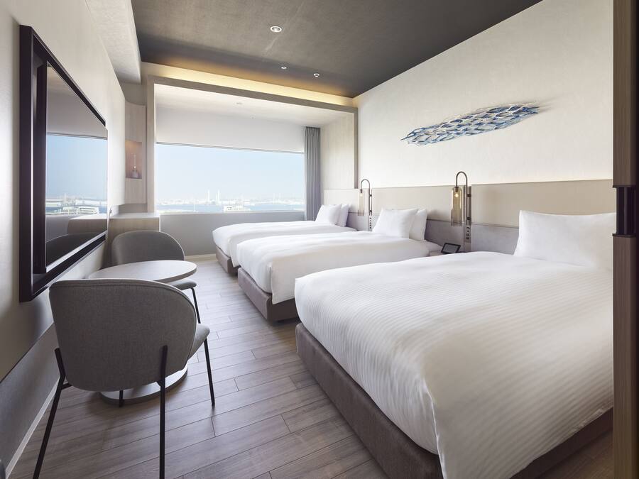Habitació d'hotel amb dos llits, escriptori i cadira. Hi ha una finestra gran amb vista a la ciutat.