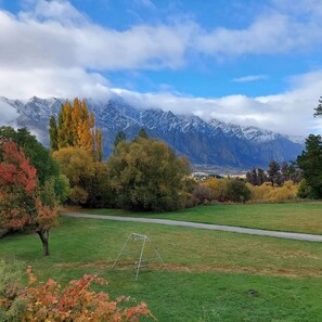 Relax in a serene grassy area with a metal swing set, surrounded by majestic mountains.