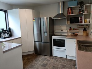 Enjoy cooking in this well-equipped kitchen with stainless steel appliances, white cabinetry, and a tiled backsplash.