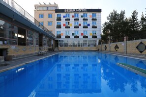 Un hotel con piscina, balcón con sillas y un letrero que dice "BEGER HOTEL".