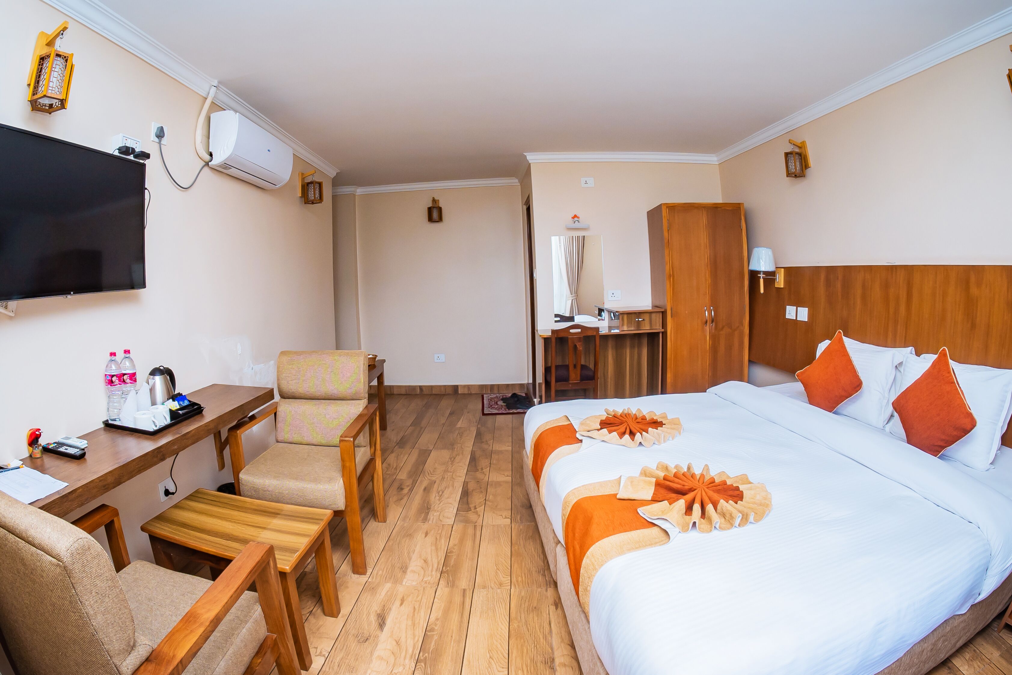 A hotel room with a bed, a desk, a chair, a television, and a wardrobe.