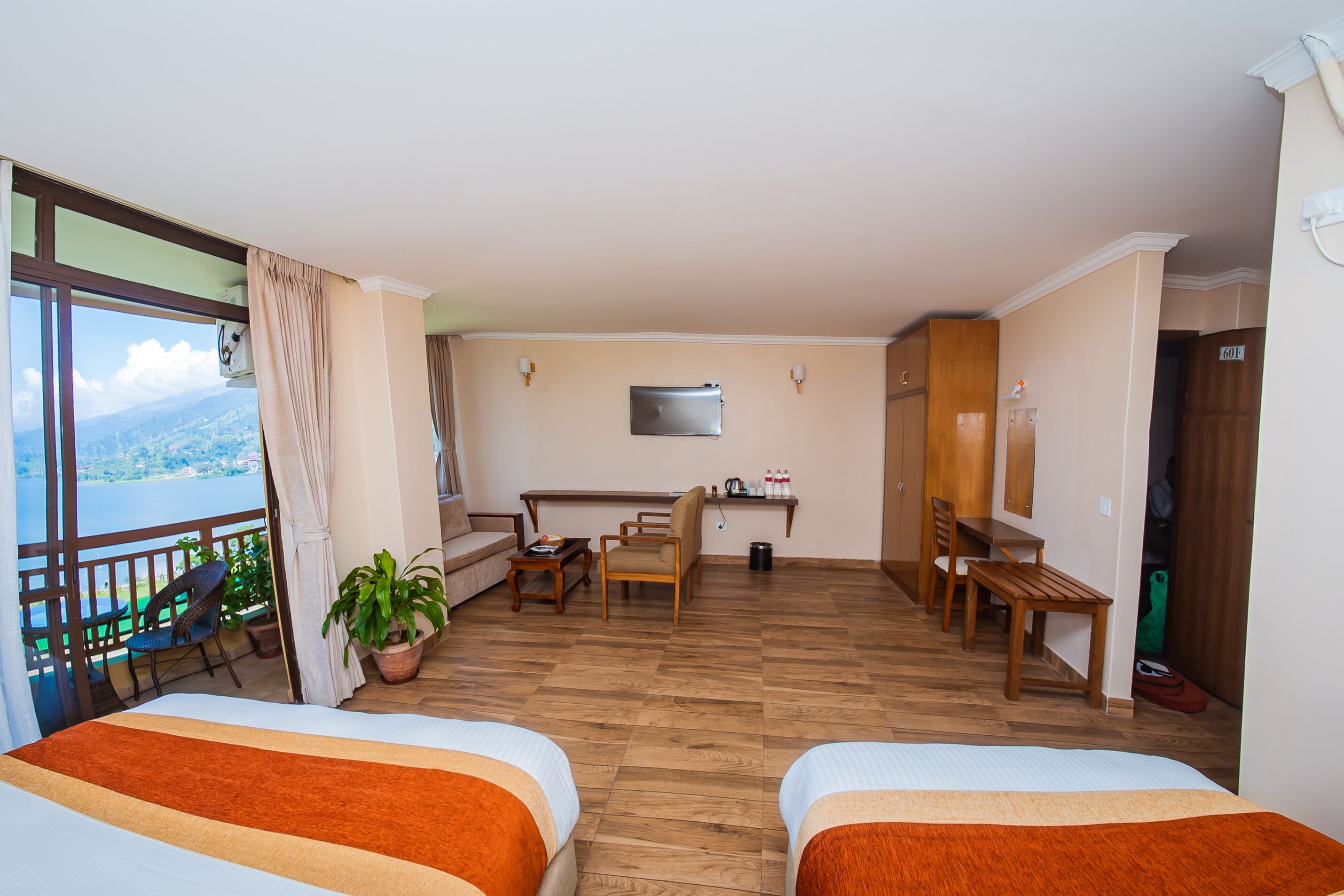 Une chambre d’hôtel avec deux lits, un balcon offrant une vue, un bureau, des chaises et une télévision.
