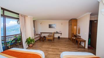Une chambre d’hôtel avec deux lits, un balcon offrant une vue, un bureau, des chaises et une télévision.