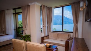A room with a bed, a sofa, a small table with a basket, and a desk with papers and a remote control. - Hotel Fewa Camp (Pokhara)