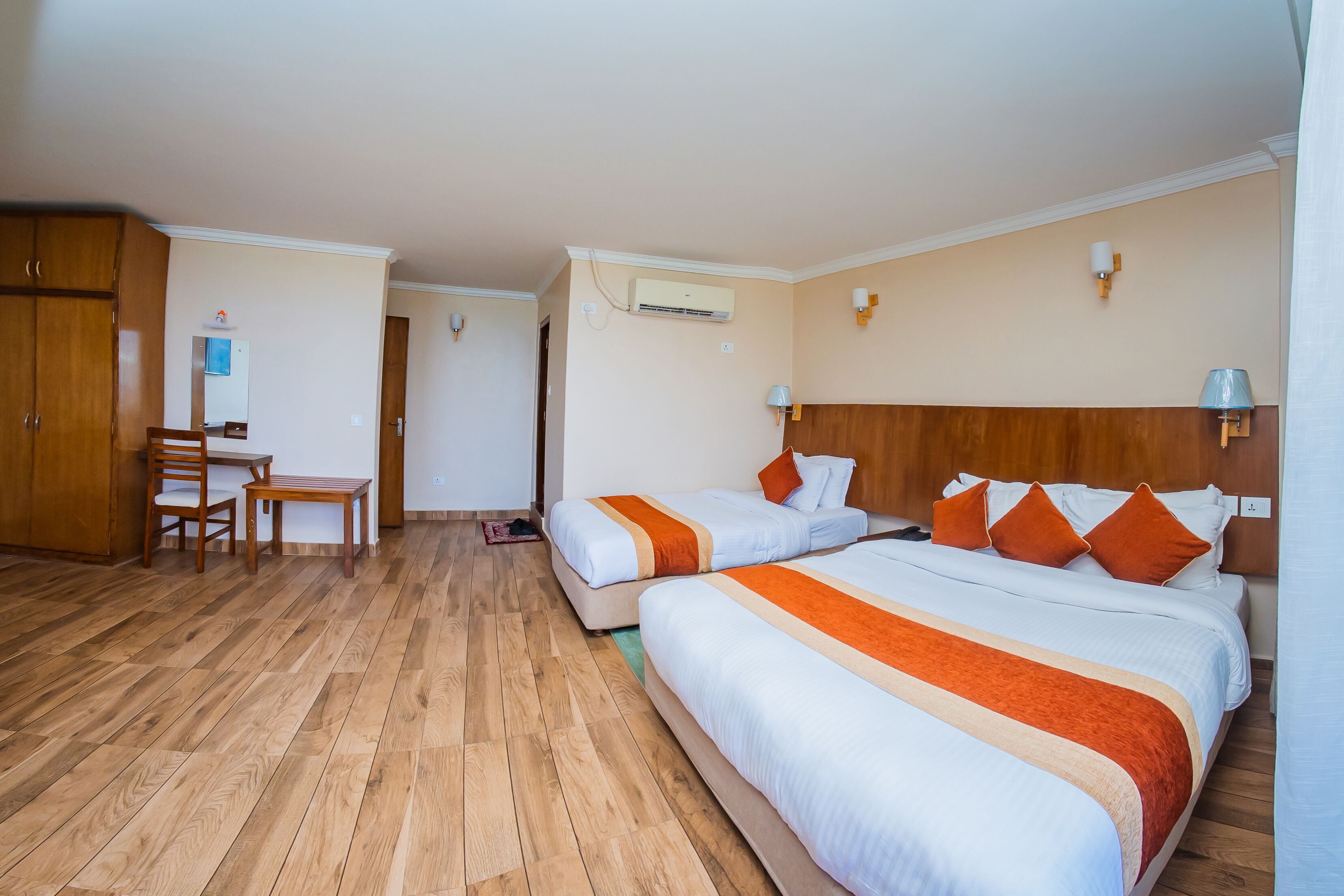 A hotel room with two beds, a desk, and a chair.