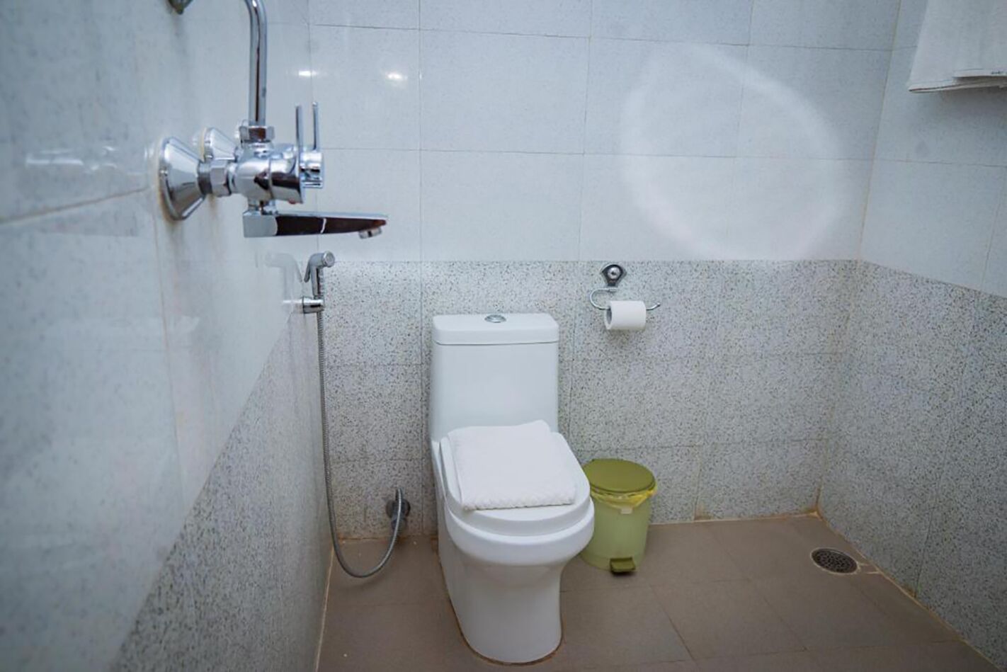 Une petite salle de bain avec des toilettes, une douche et une poubelle.