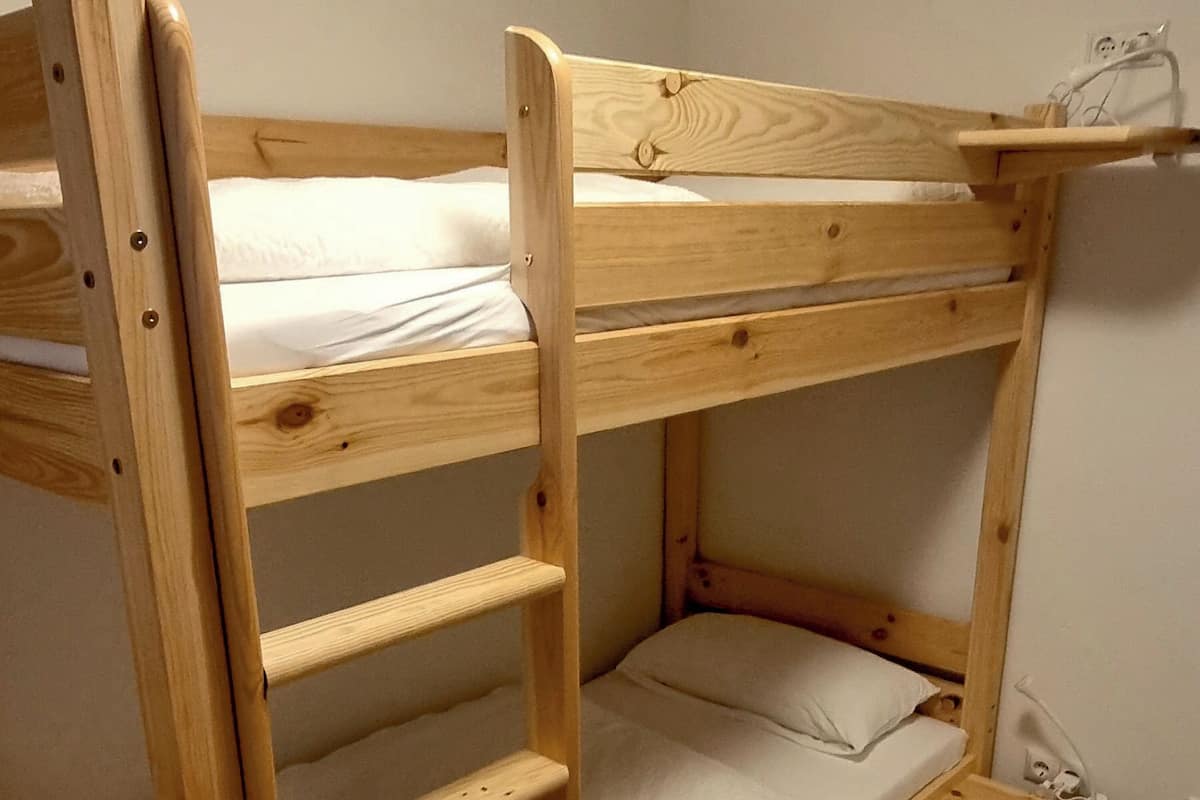 A bunk bed with a ladder, a small shelf, and a power outlet on the side.