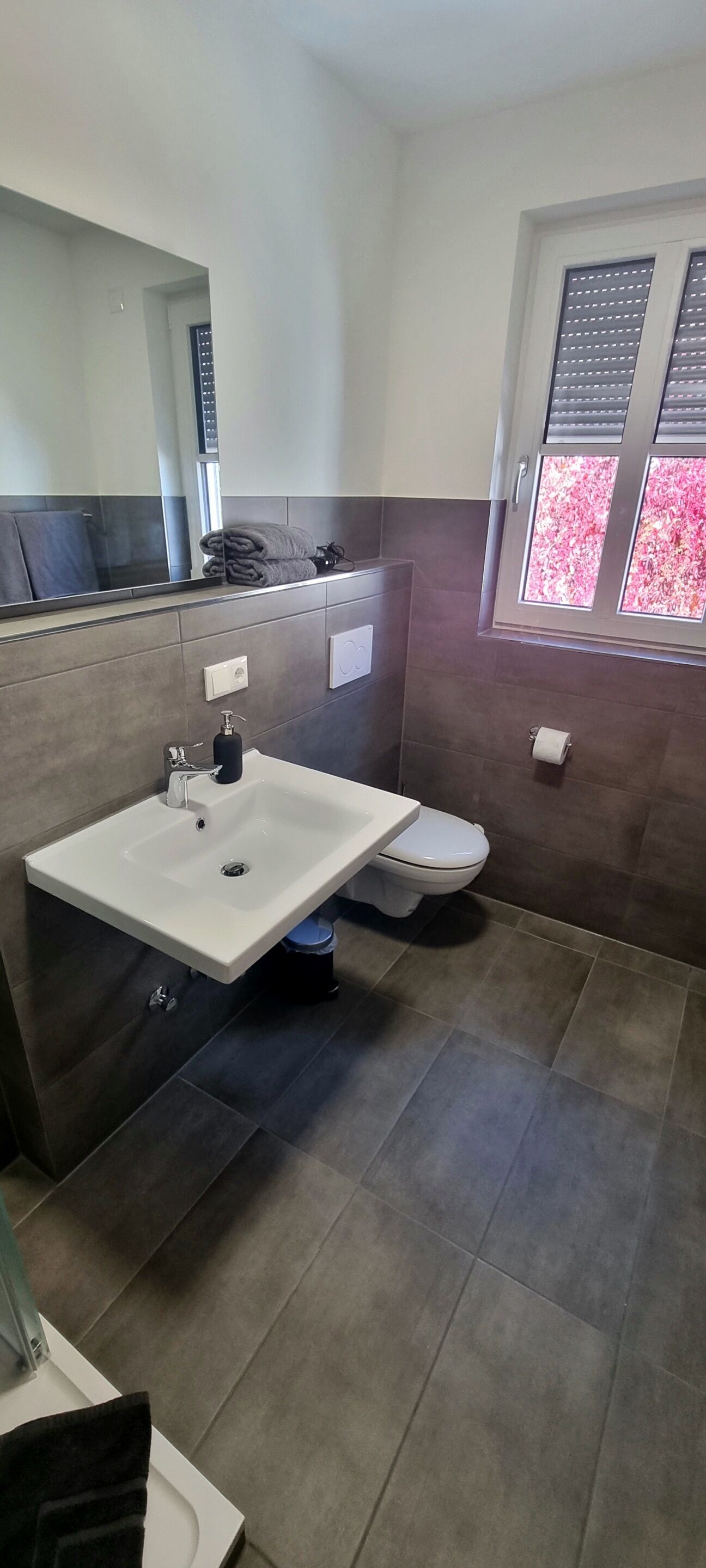 Ein modernes Badezimmer mit Waschbecken, Toilette und Fenster mit Jalousien.