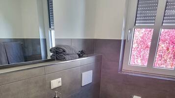 Ein modernes Badezimmer mit Waschbecken, Toilette und Fenster mit Jalousien.
