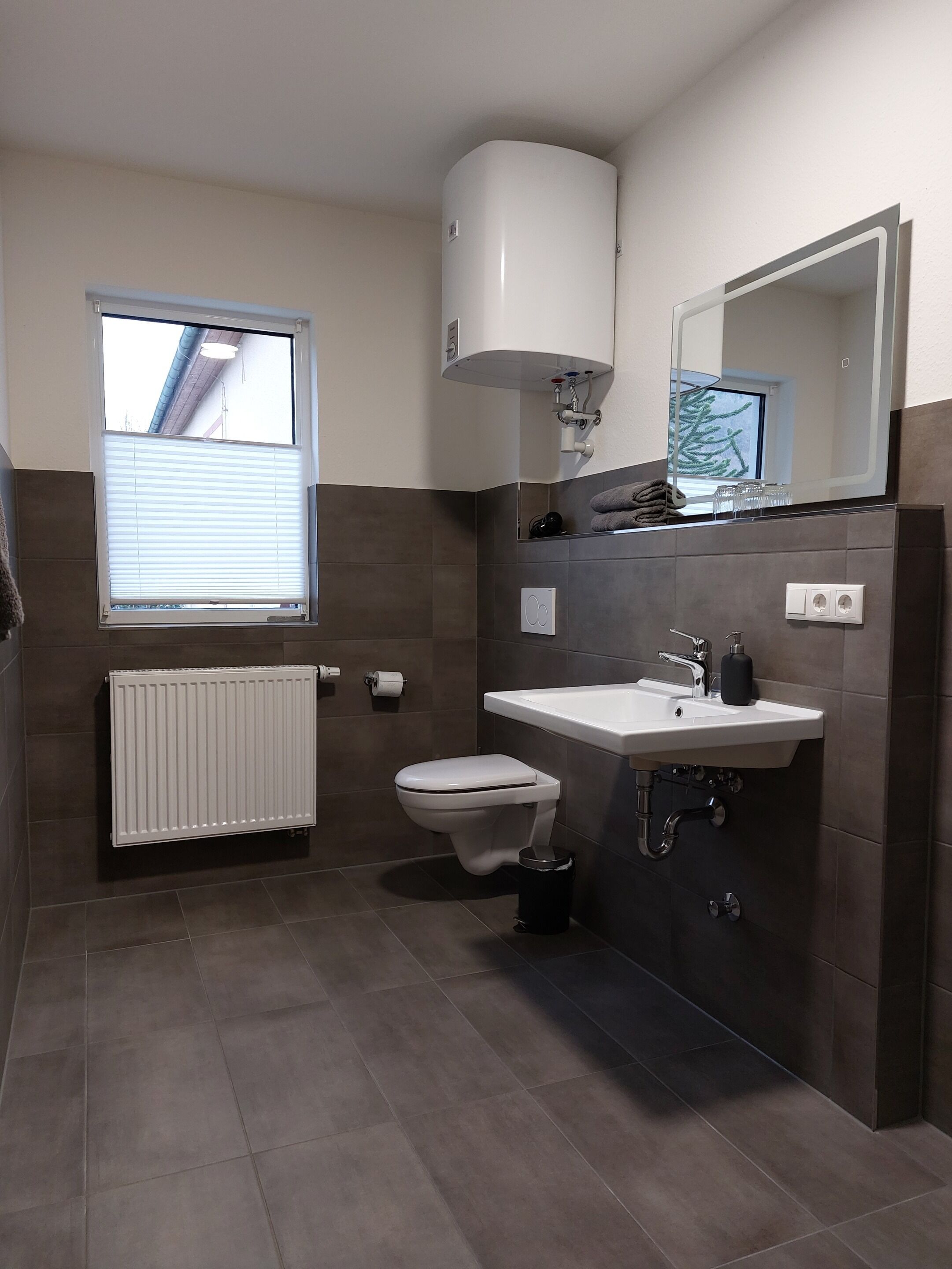 Ein modernes Badezimmer mit Toilette, Waschbecken und Fenster.