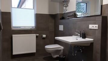 Ein modernes Badezimmer mit Toilette, Waschbecken und Fenster.
