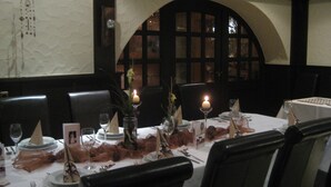 Mesa formal dispuesta para el comedor, con mantel blanco, sillas negras y centros de mesa con velas.