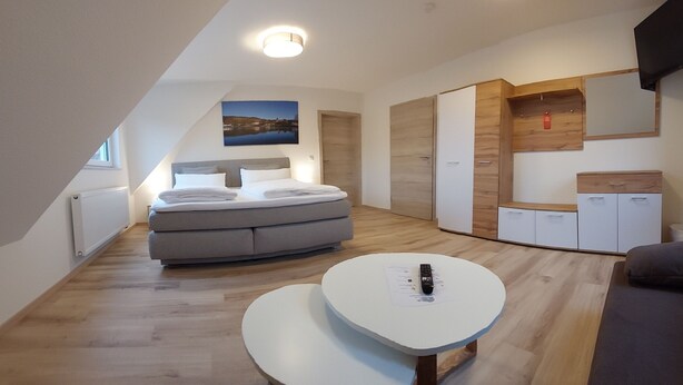 Una habitación moderna y bien iluminada con cama, sofá, una mesita y armarios empotrados.