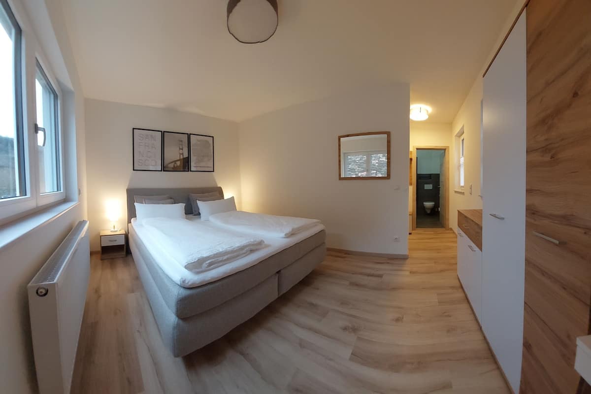 A modern bedroom with a bed, bedside table, and a window.