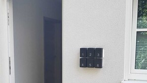 Entrada de un edificio con puerta, una ventana pequeña y cerradura electrónica.