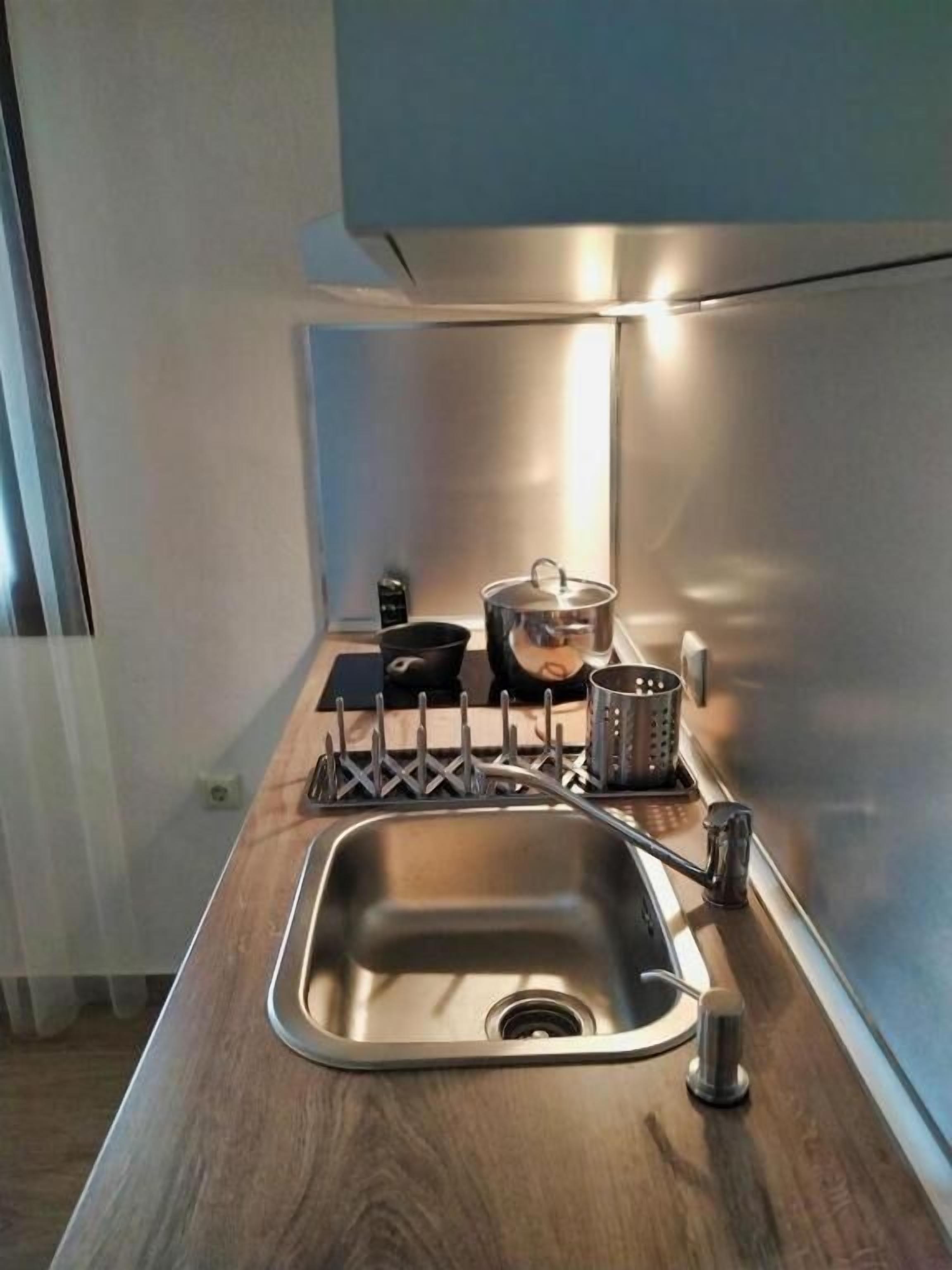 A modern kitchen with a stainless steel sink, wooden countertop, and a pot on the stove.