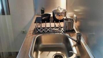A modern kitchen with a stainless steel sink, wooden countertop, and a pot on the stove.