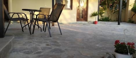 An outdoor seating area with stone flooring, a door, and potted plants.
