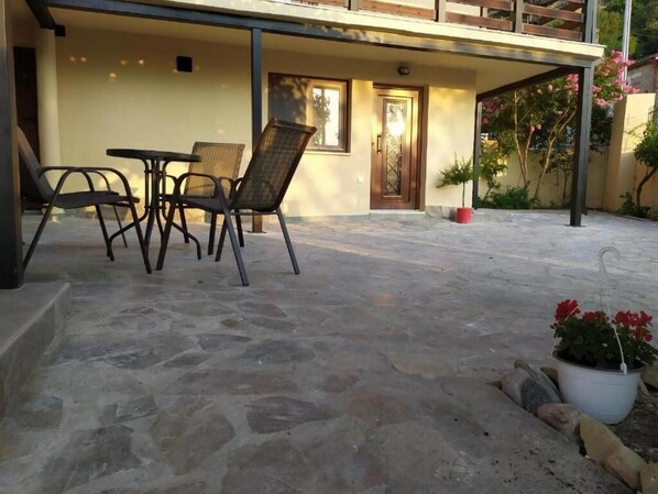 An outdoor seating area with stone flooring, a door, and potted plants. - Guesthouse Kastelia (Kalabaka)
