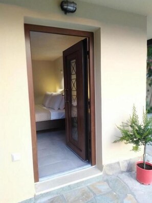 A doorway leading into a room with a bed and a potted plant. - Guesthouse Kastelia (Kalabaka)
