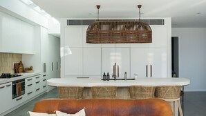Una cucina moderna con mobili bianchi, un'isola centrale con sgabelli da bar e un lampadario a sospensione.