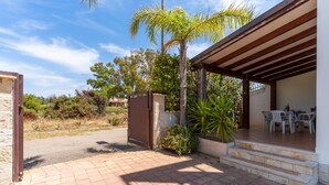 A covered outdoor area with a patio, steps leading to a table and chairs, and a small garden with a palm tree and shrubs. - 2404 Villa Cieloazzurro - Bilo by Barbarhouse (Nardò)