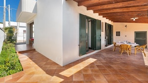 A patio area with a tiled floor, a table with chairs, and a wooden ceiling. - 2753 Villa Evelin by Barbarhouse (Porto Cesareo)
