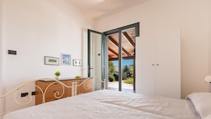 A bedroom with a bed, a dresser, and a door leading to an outdoor area. - 2753 Villa Evelin by Barbarhouse (Porto Cesareo)