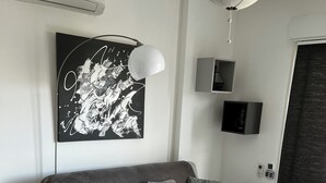 A modern living room with a grey sofa, a coffee table, a wall-mounted TV, and a ceiling light fixture. - Casa PETRA SALGA (CORTE)