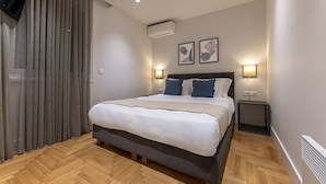 Une chambre d’hôtel moderne avec un grand lit, un plancher en bois et deux lampes de chevet.