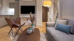 Un salon moderne comprenant un canapé, une table basse, un fauteuil en cuir et un téléviseur fixé au mur.