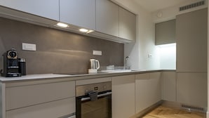 Une cuisine moderne avec des meubles de couleur grise, un four encastré, une machine à café et une bouilloire.