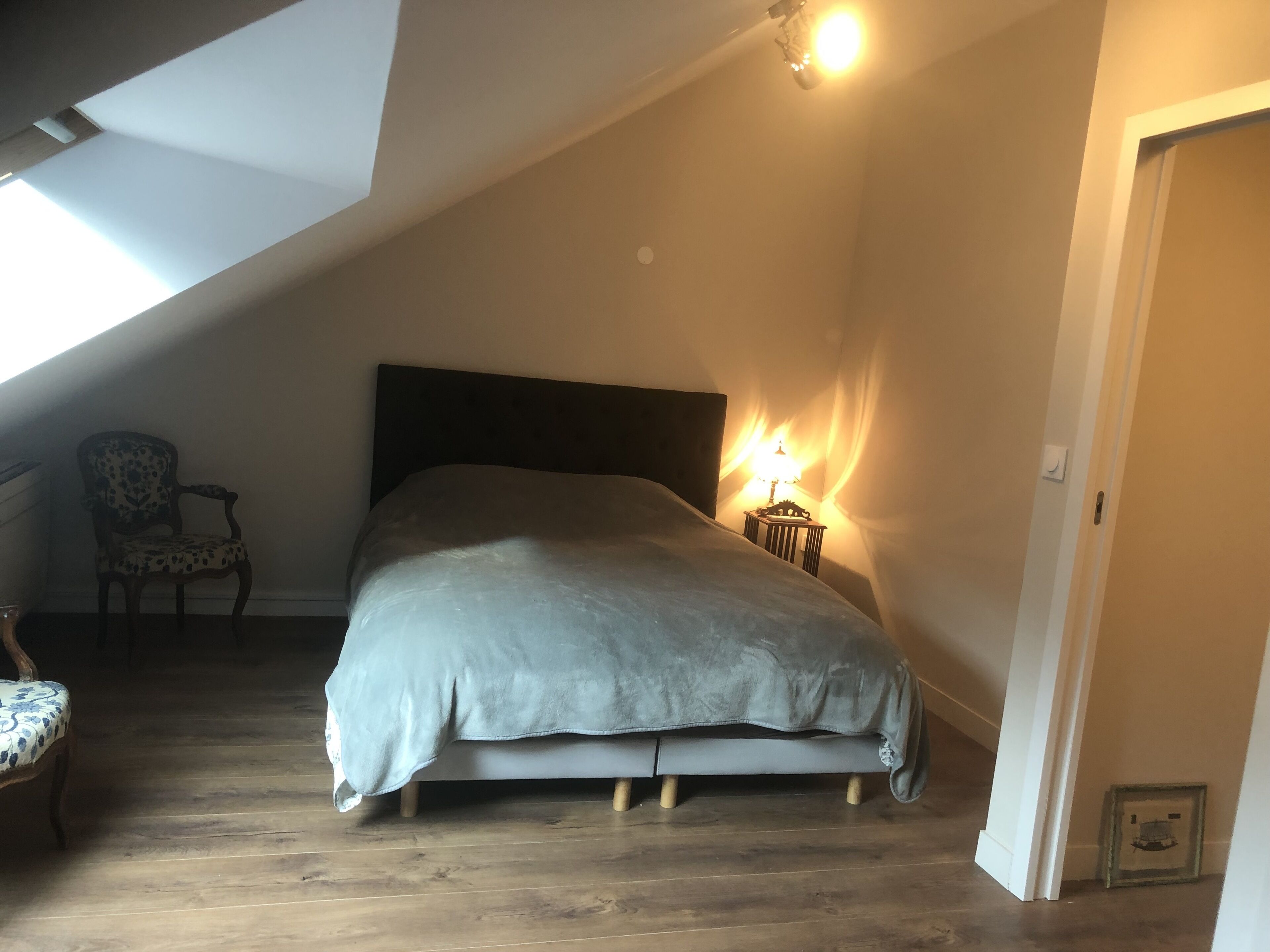 A bedroom with a bed, a chair, and a lamp.