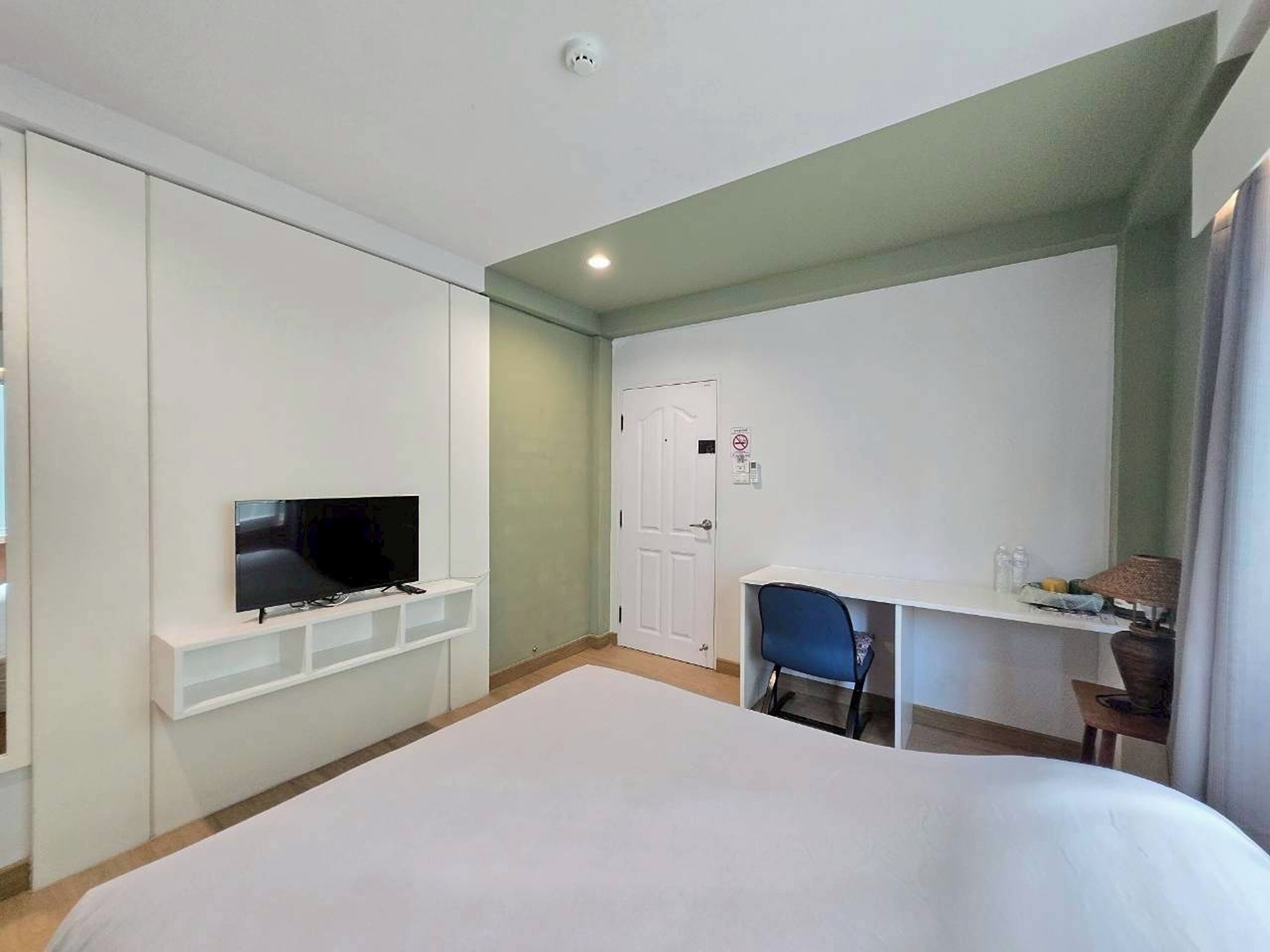 A hotel room with a bed, a TV, a desk, and a chair.