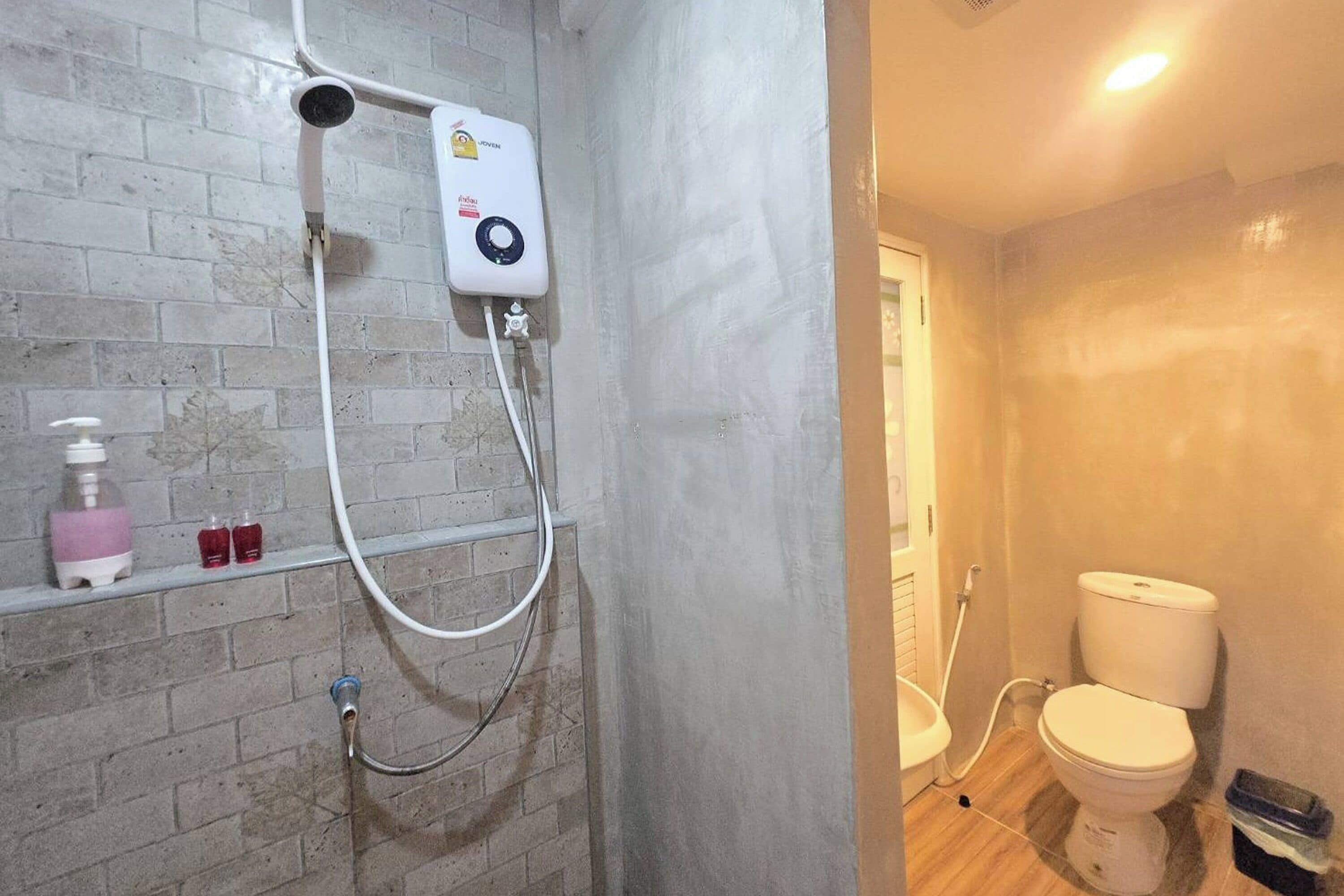 Ein Badezimmer mit Dusche, Toilette und einer Ziegelwand.