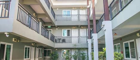 Un edificio residencial de varios niveles con balcones, plantas en macetas y un patio central.