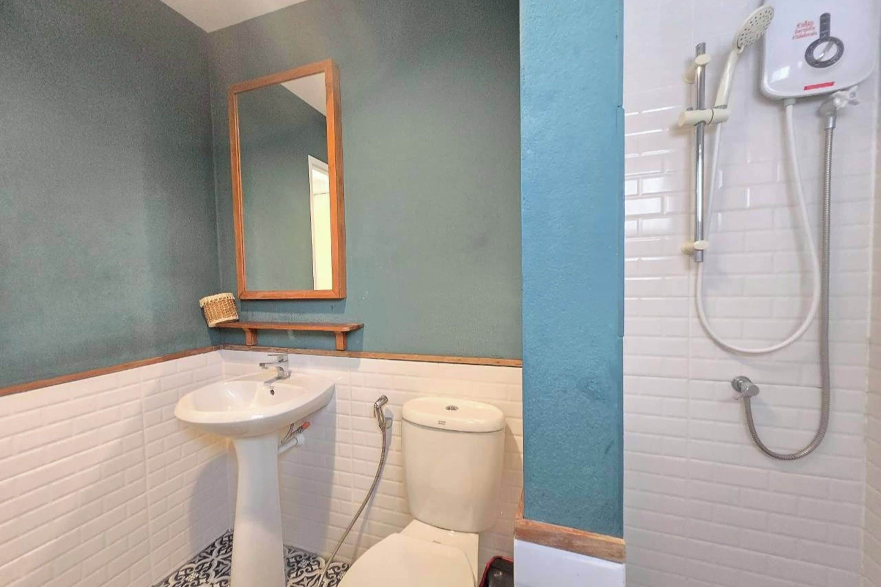 A bathroom with a pedestal sink, toilet, and a shower with a handheld showerhead.