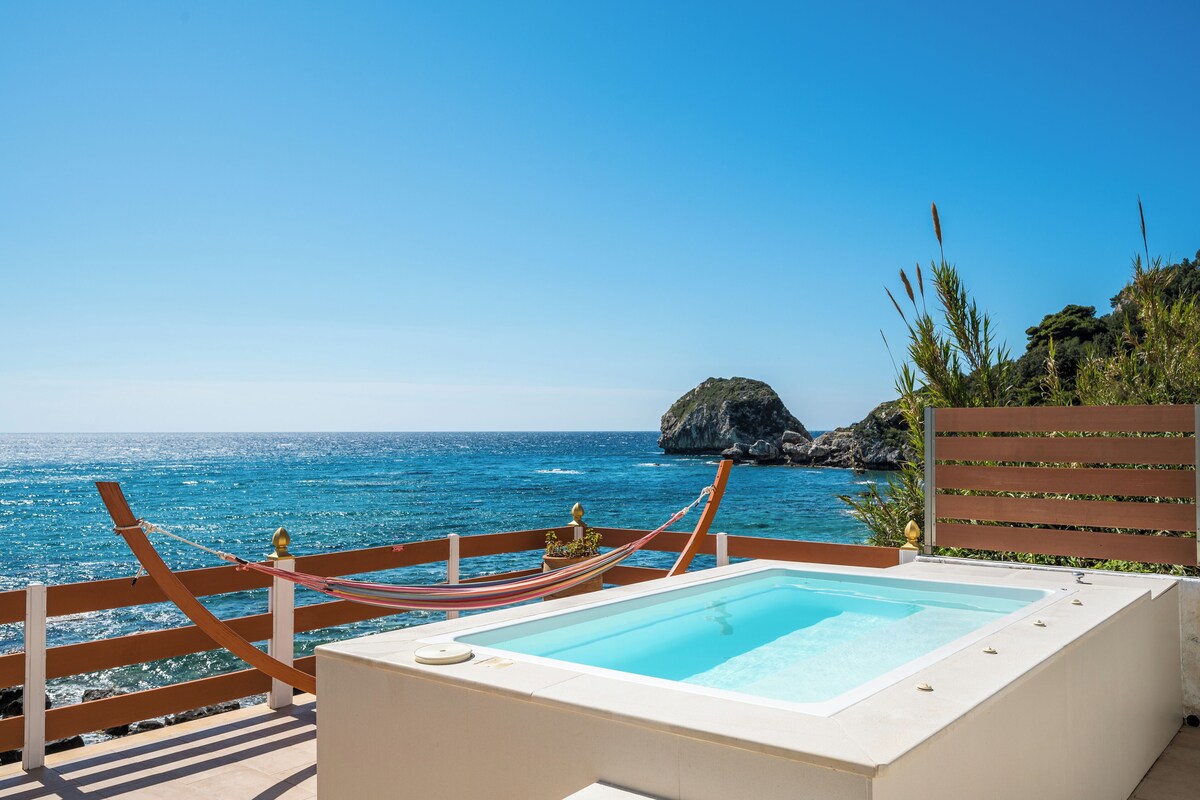 A pool area with a view of the ocean and a rocky island.
