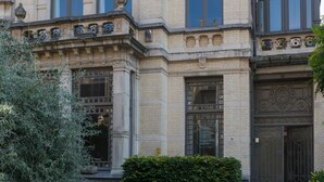 Un edificio histórico con detalles arquitectónicos ornamentales, un camino de adoquines y un seto bien cuidado.