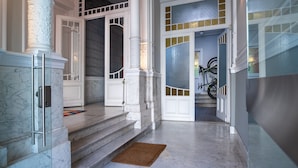 Una entrada imponente con escalones de mármol, puertas blancas y una puerta de vidrio que da a una escalera.