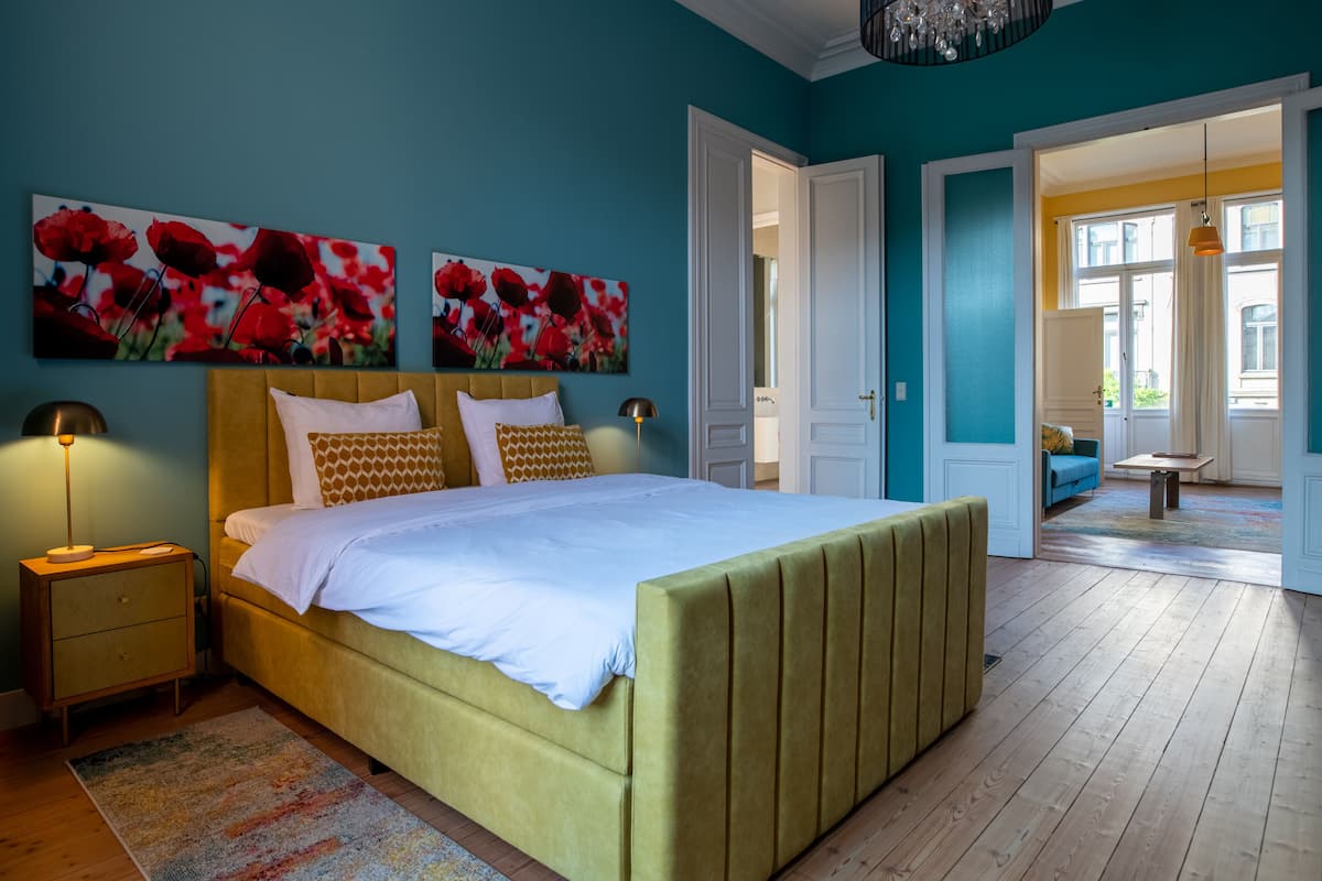 A bedroom with a bed, nightstands, and a view of a living area.
