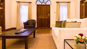 Une pièce chaleureuse avec un plafond en bois, une porte en bois, un canapé, un fauteuil, une table basse et une petite fenêtre.