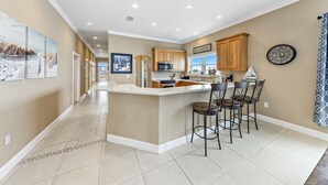 Une cuisine spacieuse avec un îlot central, des armoires en bois et une grande horloge au mur.