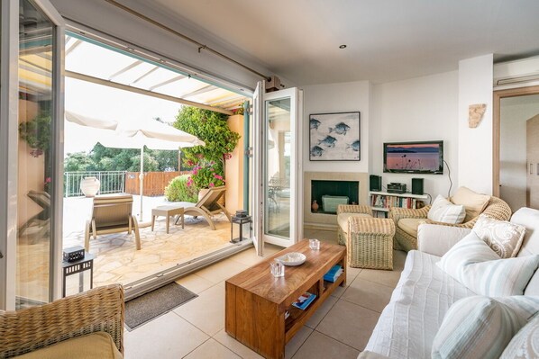 A spacious living area with a sliding glass door leading to an outdoor patio, a fireplace, and a television on the wall.