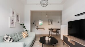 Una sala de estar moderna con sofá, mesa de centro, televisor y obras de arte en la pared.
