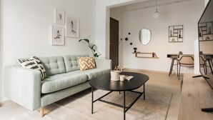 Una sala de estar moderna con un sofá verde claro, una mesa de centro redonda y un comedor con mesa y sillas de madera.