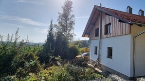 Una casa con techo inclinado, fachada de madera y varias ventanas.